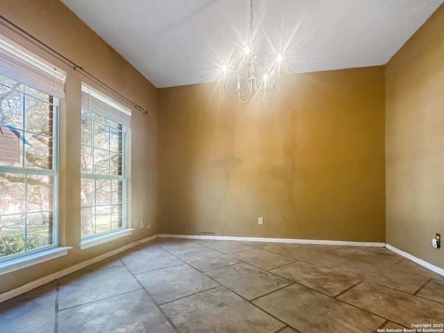 spare room featuring baseboards and an inviting chandelier