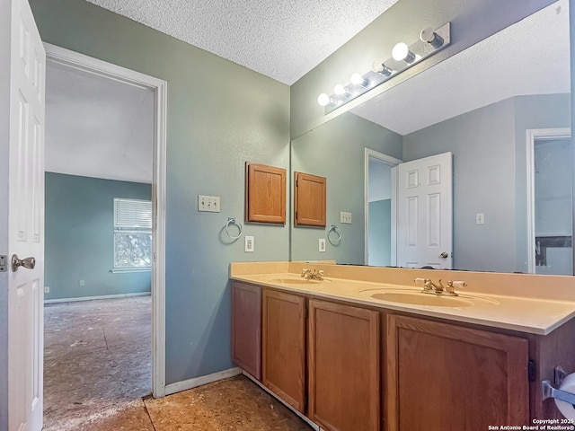 bathroom featuring double vanity, a textured ceiling, baseboards, and a sink