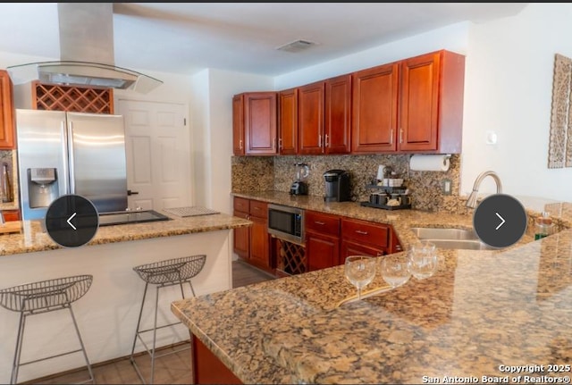 kitchen featuring island range hood, a sink, light stone countertops, stainless steel appliances, and backsplash