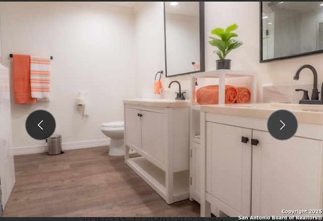 bathroom featuring toilet, vanity, baseboards, and wood finished floors