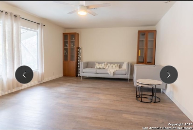 living area with a ceiling fan and wood finished floors