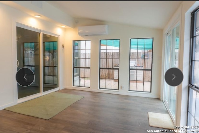 doorway to outside featuring vaulted ceiling, a wall unit AC, and wood finished floors