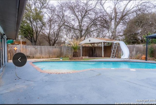 view of swimming pool with a gazebo, a water slide, a fenced backyard, and a fenced in pool