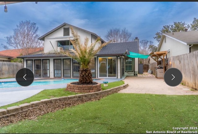 back of property with a fenced backyard, a sunroom, a lawn, a fenced in pool, and a patio area