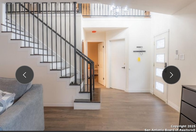 entryway with baseboards, a high ceiling, stairway, and wood finished floors