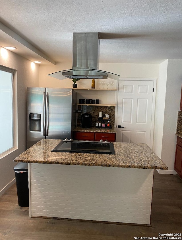 kitchen featuring stainless steel refrigerator with ice dispenser, dark wood-type flooring, black electric cooktop, dark stone counters, and island exhaust hood