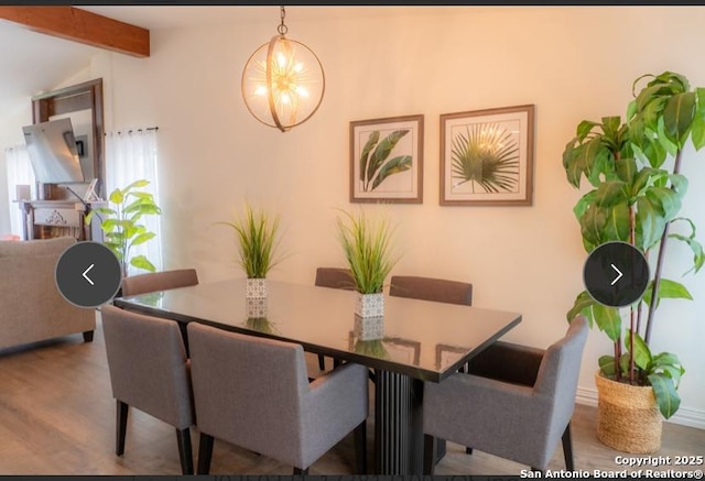 dining area featuring vaulted ceiling with beams, a chandelier, and wood finished floors