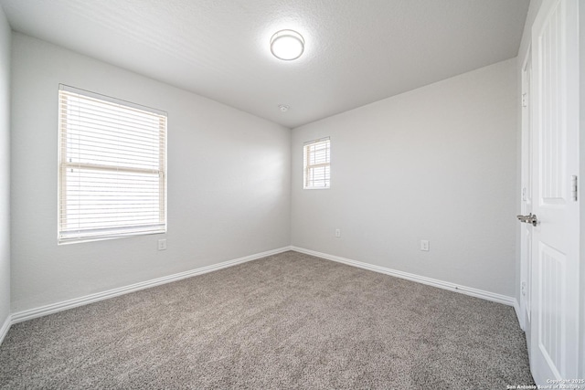 spare room with carpet floors, a textured ceiling, and baseboards