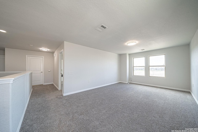 carpeted spare room with visible vents, a textured ceiling, and baseboards