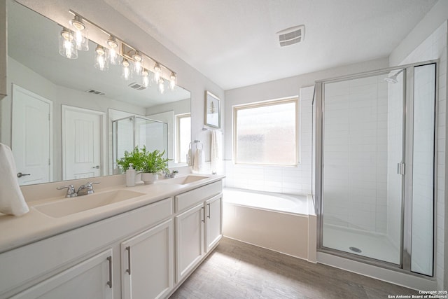 full bath featuring double vanity, wood finished floors, a sink, and visible vents