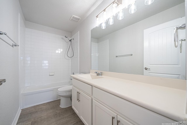 bathroom featuring visible vents, toilet, washtub / shower combination, vanity, and wood finished floors