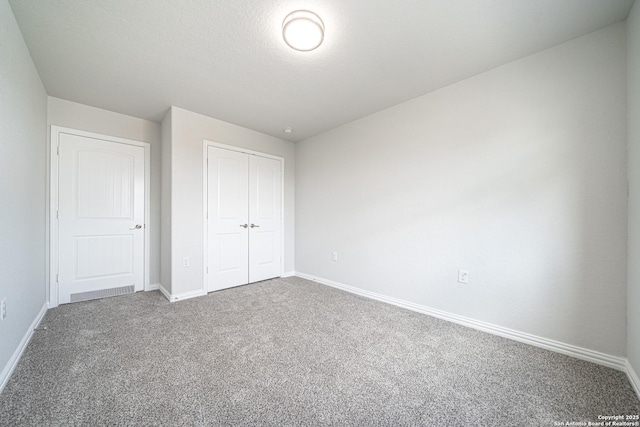 unfurnished bedroom with a textured ceiling, a closet, carpet flooring, and baseboards