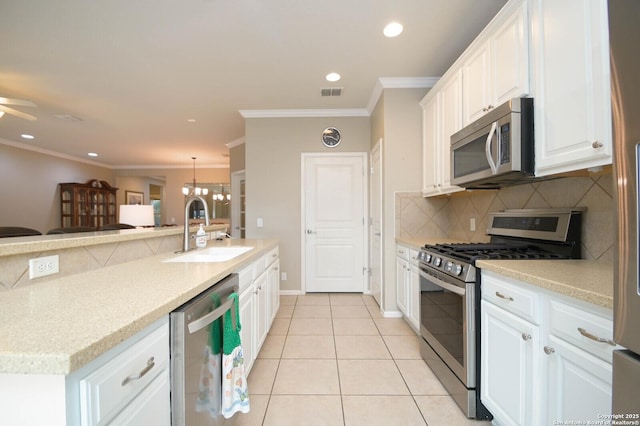 kitchen featuring stainless steel appliances, white cabinetry, a sink, and hanging light fixtures