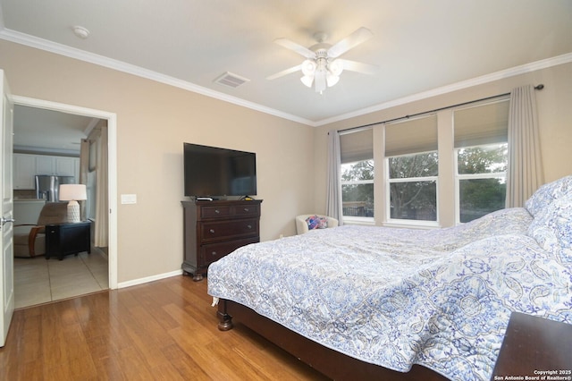 bedroom featuring baseboards, visible vents, ornamental molding, and wood finished floors