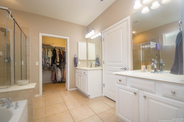 full bathroom featuring tile patterned flooring, two vanities, a sink, a shower stall, and a walk in closet