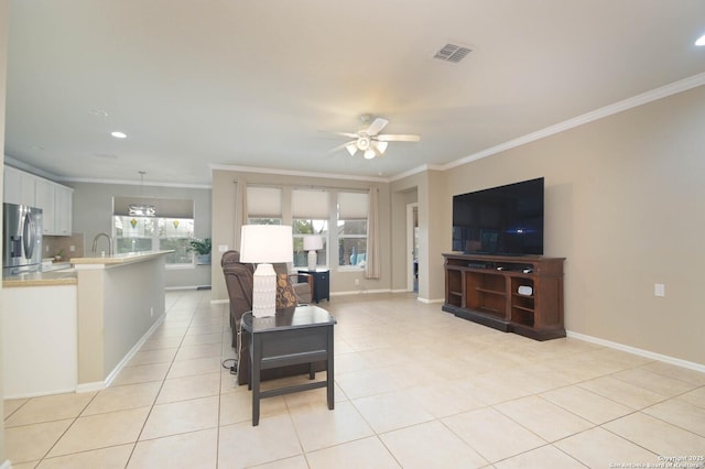 living area with light tile patterned floors, baseboards, visible vents, ceiling fan, and crown molding