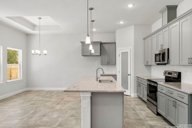 kitchen featuring gray cabinets, pendant lighting, stainless steel appliances, and a sink