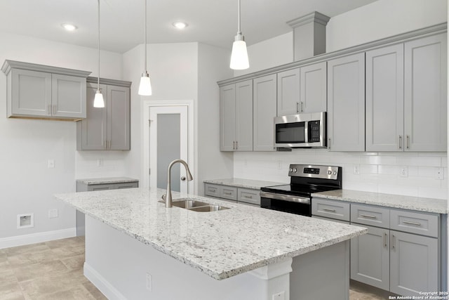 kitchen featuring a kitchen island with sink, appliances with stainless steel finishes, a sink, and decorative light fixtures