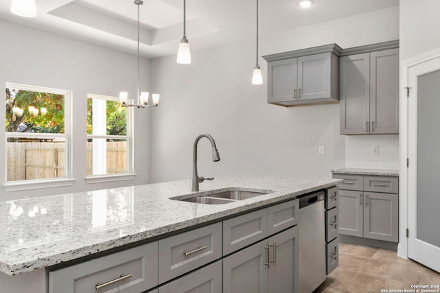 kitchen featuring a kitchen island with sink, gray cabinetry, a sink, stainless steel dishwasher, and light stone countertops