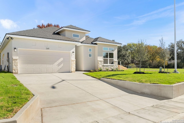 prairie-style home with stone siding, concrete driveway, a front yard, and stucco siding