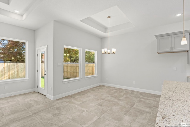 unfurnished dining area featuring a chandelier, recessed lighting, a raised ceiling, and baseboards