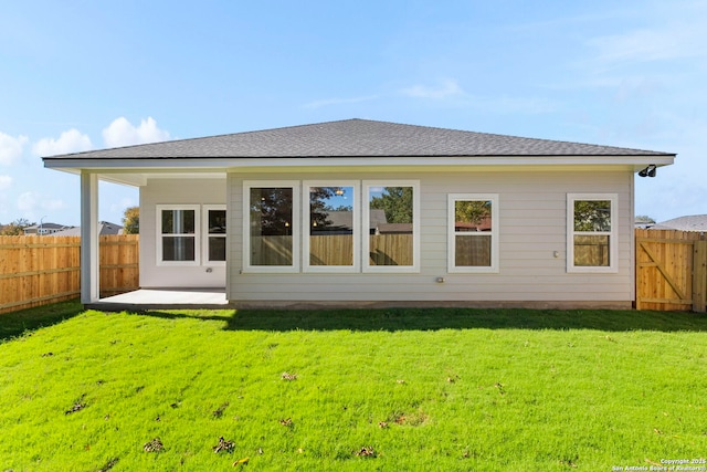 back of property featuring a yard, a patio, a fenced backyard, and roof with shingles