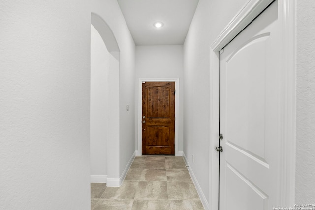 doorway with arched walkways and baseboards