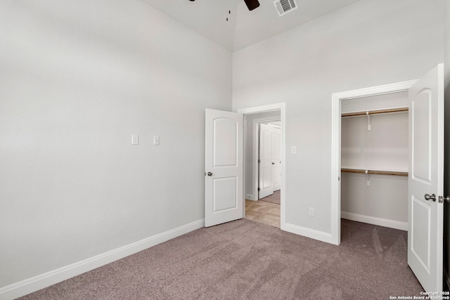 unfurnished bedroom with light carpet, visible vents, baseboards, a spacious closet, and a closet