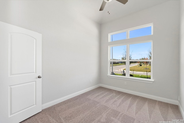 carpeted empty room featuring ceiling fan and baseboards