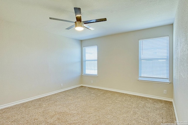 spare room featuring ceiling fan, a textured ceiling, light carpet, and baseboards