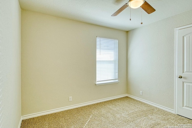 carpeted spare room with ceiling fan and baseboards