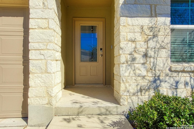 property entrance featuring a garage and stone siding