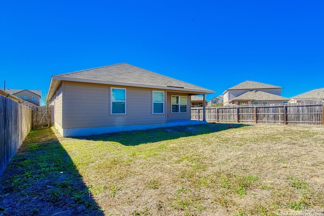 rear view of house with a yard and a fenced backyard