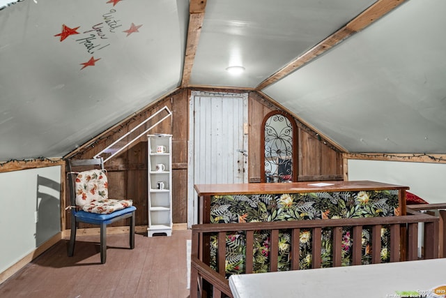 additional living space featuring lofted ceiling, wood walls, and wood finished floors