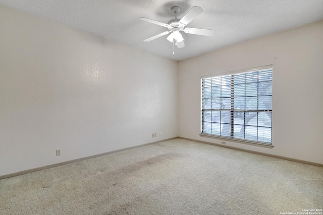 carpeted spare room featuring ceiling fan, a textured ceiling, and baseboards