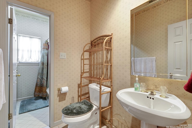 full bath with a shower with curtain, toilet, a sink, tile patterned flooring, and wallpapered walls