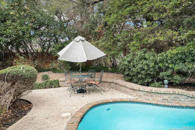 outdoor pool with outdoor dining space and a fenced backyard