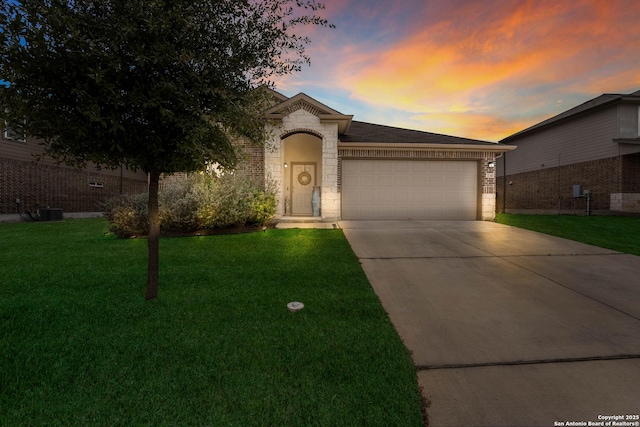 view of front of home featuring concrete driveway, a yard, an attached garage, and brick siding