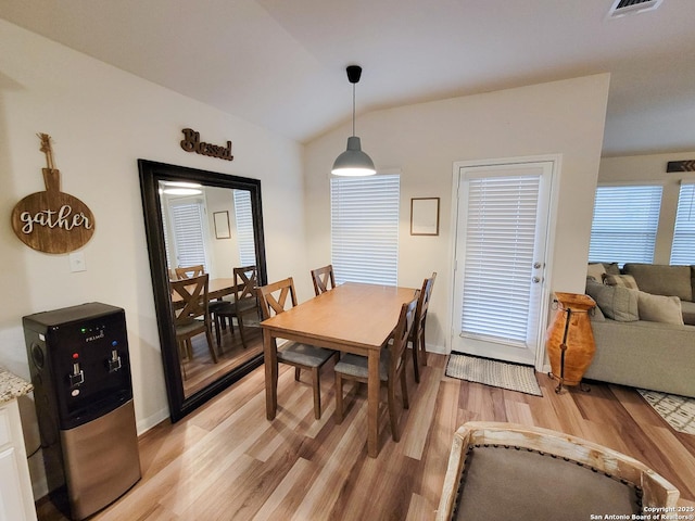 dining room with light wood-style floors, visible vents, vaulted ceiling, and baseboards