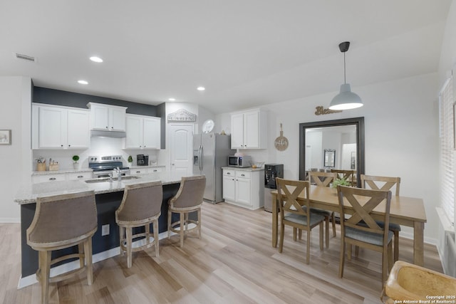 kitchen featuring decorative light fixtures, visible vents, appliances with stainless steel finishes, white cabinetry, and light stone countertops