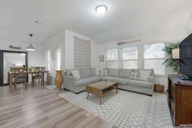 living area featuring lofted ceiling, visible vents, and a wealth of natural light