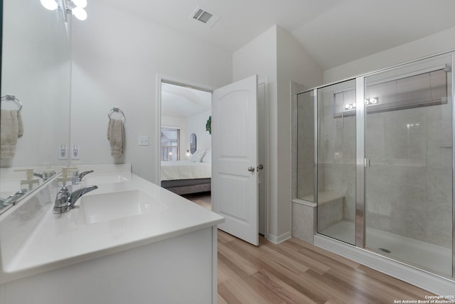 ensuite bathroom with visible vents, ensuite bathroom, a stall shower, a sink, and wood finished floors