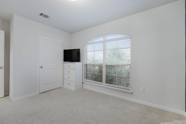 unfurnished bedroom featuring visible vents, light carpet, and baseboards