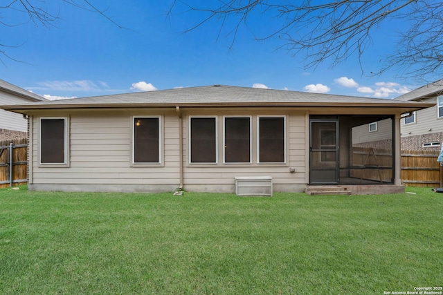 back of property featuring roof with shingles, a lawn, and fence