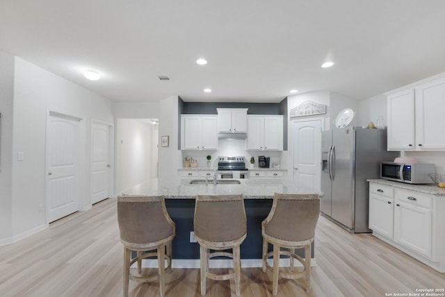 kitchen featuring appliances with stainless steel finishes, white cabinetry, and light stone countertops