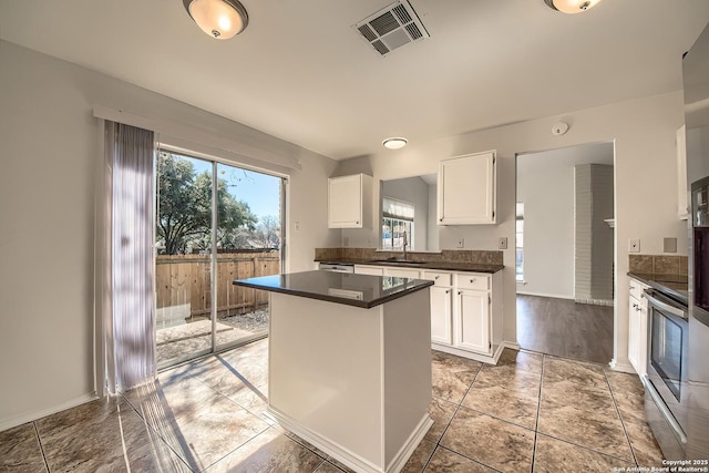 kitchen featuring stainless steel electric range oven, dark countertops, visible vents, and white cabinets