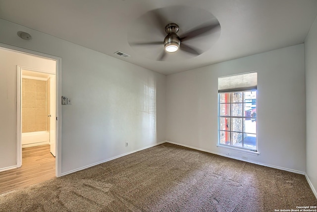 empty room with ceiling fan, carpet floors, visible vents, and baseboards