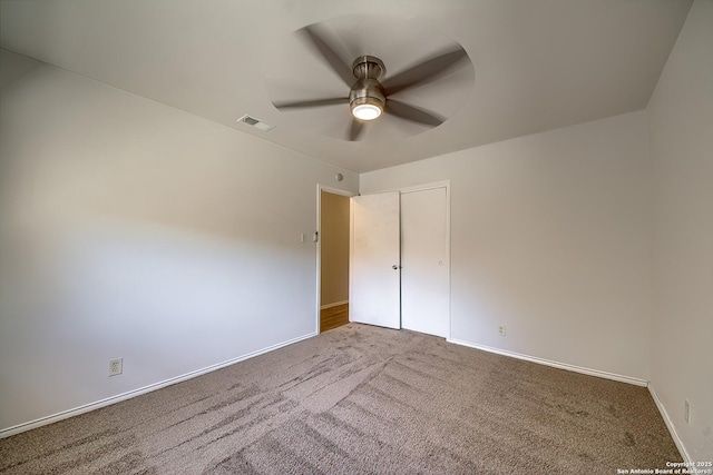 carpeted spare room with ceiling fan, visible vents, and baseboards