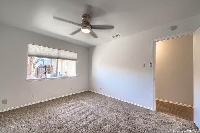 empty room with baseboards, carpet floors, visible vents, and a ceiling fan