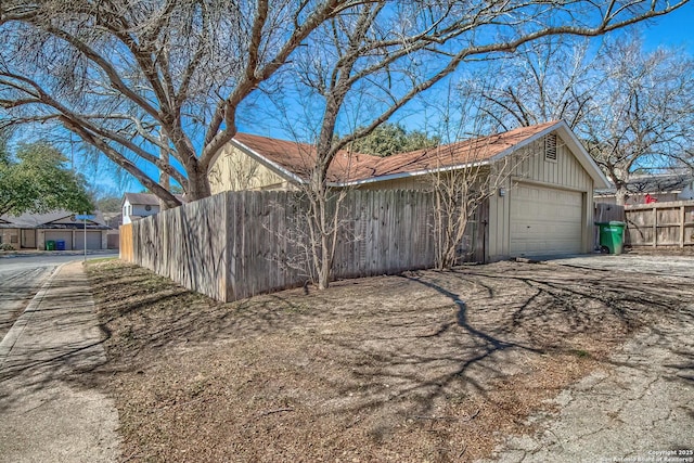 view of side of property featuring a garage and fence